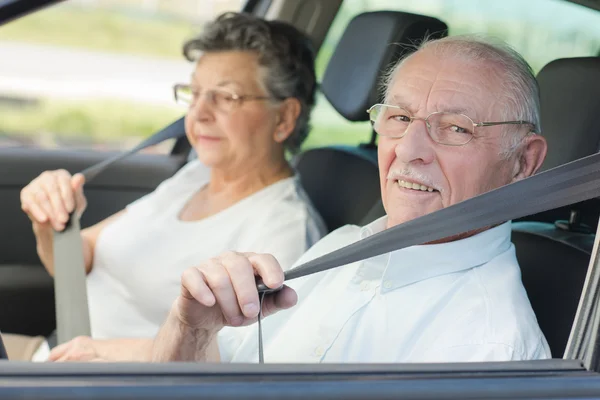 Elderly couple putting on their seatbelts — Stock Photo, Image