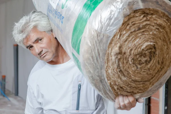 Builder carrying roll of insulation — Stock Photo, Image