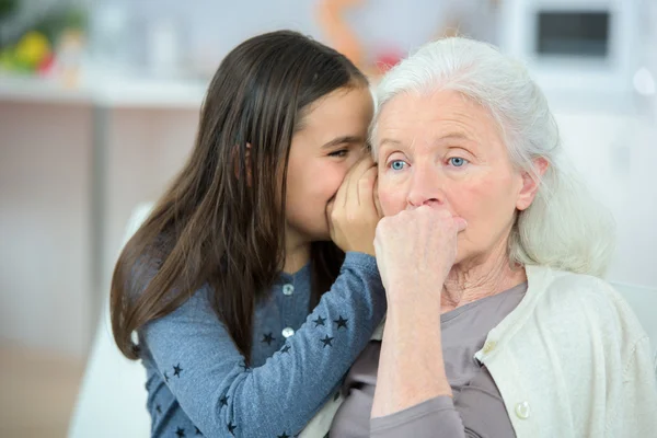 Petite fille et grand-mère chuchotant des secrets — Photo