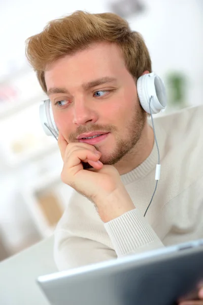 Surfen im Internet, während er über Kopfhörer Musik hört — Stockfoto