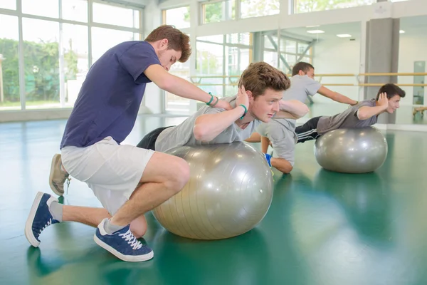 Two men being held in position on aerobic balls — Stock Photo, Image