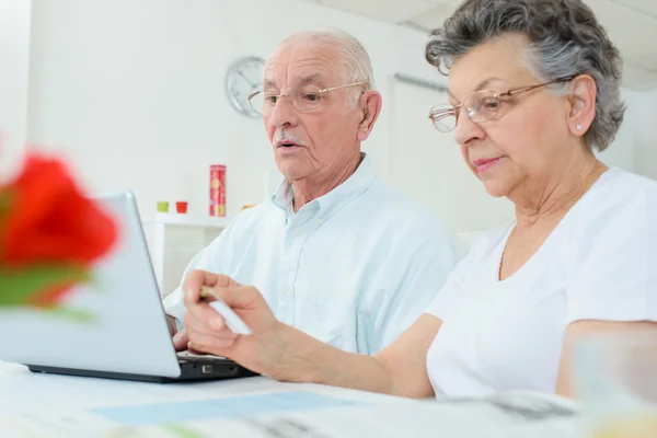 Пожилая пара за компьютером, жена держит кредитку — стоковое фото