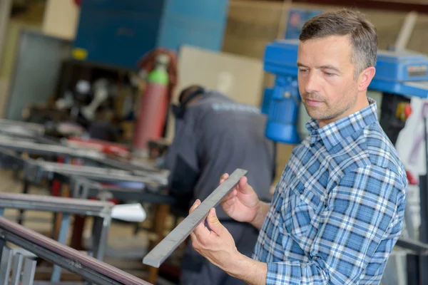 Workman bedrijf lengte van metaal — Stockfoto