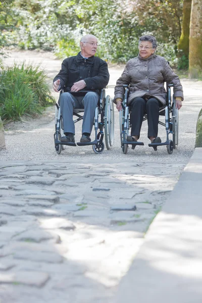 Coppia anziana passeggiata in sedia a rotelle — Foto Stock