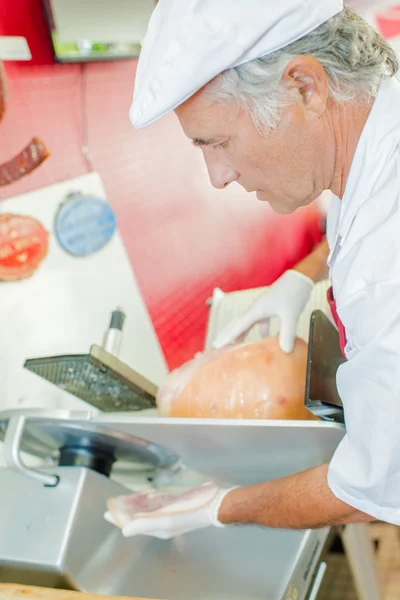 Metzger schneidet etwas Schinken — Stockfoto