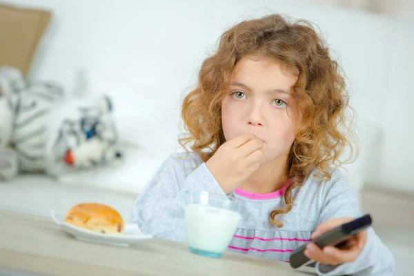 Niña viendo la televisión mientras desayuna —  Fotos de Stock