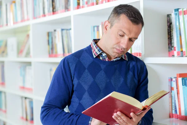 Man stod tittar på bok i biblioteket — Stockfoto