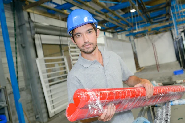 Homem segurando dois longos tubos vermelhos — Fotografia de Stock