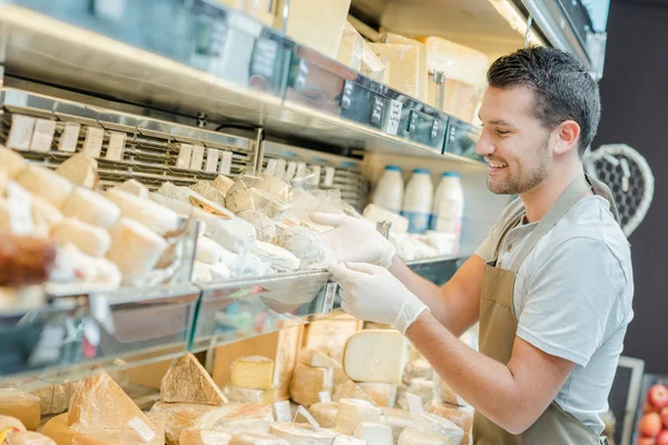 Помощник продавца пополняет запасы сыра — стоковое фото