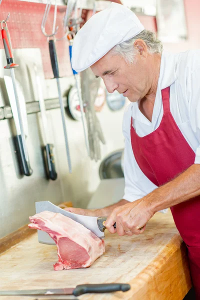 Slager snijden vlees en schort — Stockfoto