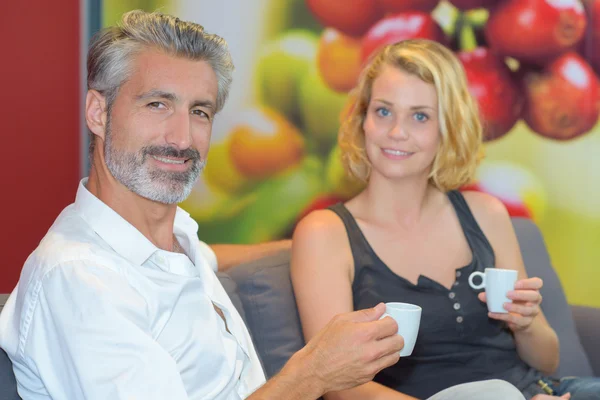 Couple sat on couch holding cup of drink — Stock Photo, Image