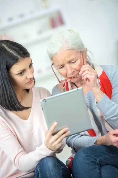 Помощь пожилой женщине в использовании планшетного компьютера — стоковое фото