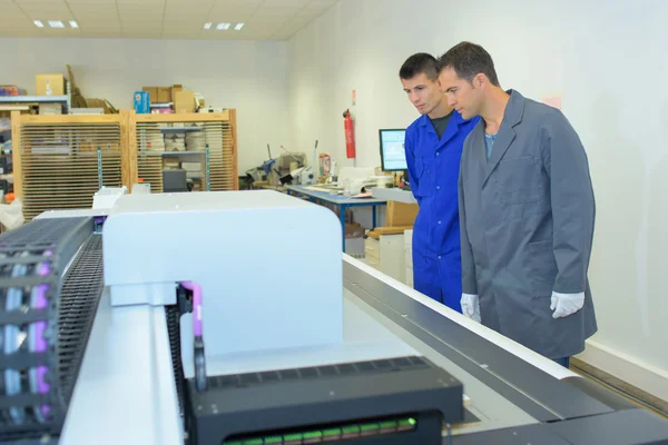 Dois homens observando a máquina de impressão — Fotografia de Stock