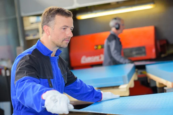 Workman bedrijf blad van metaal — Stockfoto