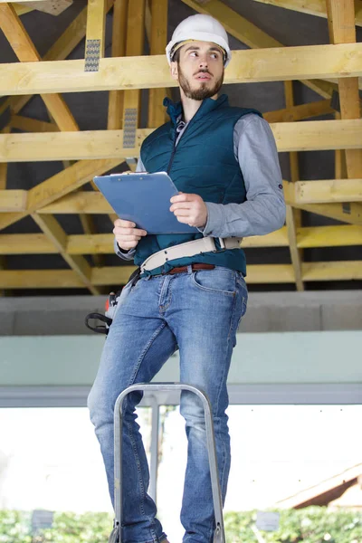 Mann Auf Leiter Hält Klemmbrett Und Kontrolliert Dach — Stockfoto