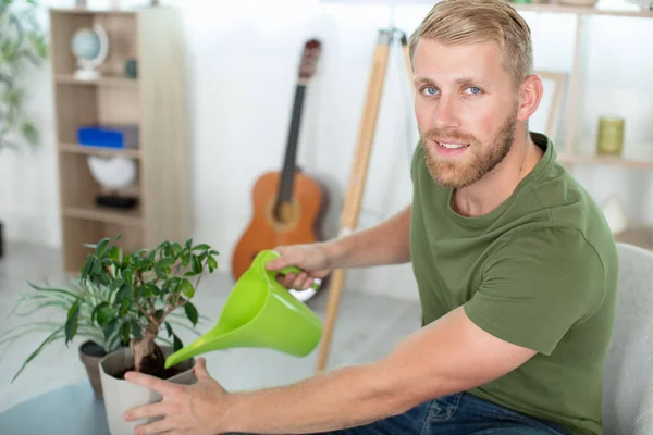 年轻英俊的男子喷洒室内植物 — 图库照片