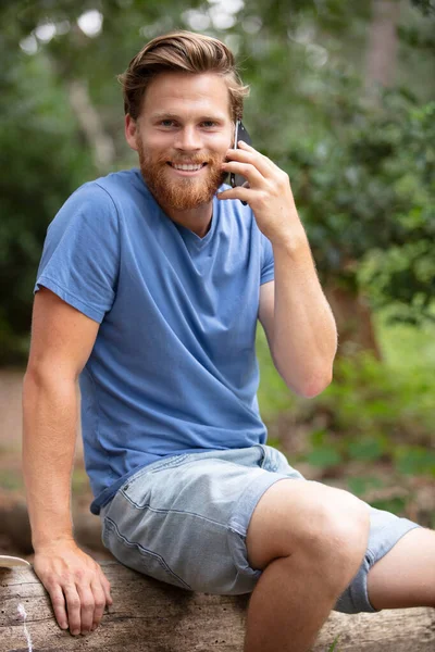 Homme Assis Sur Tronc Arbre Dans Forêt Utilisant Téléphone Mobile — Photo