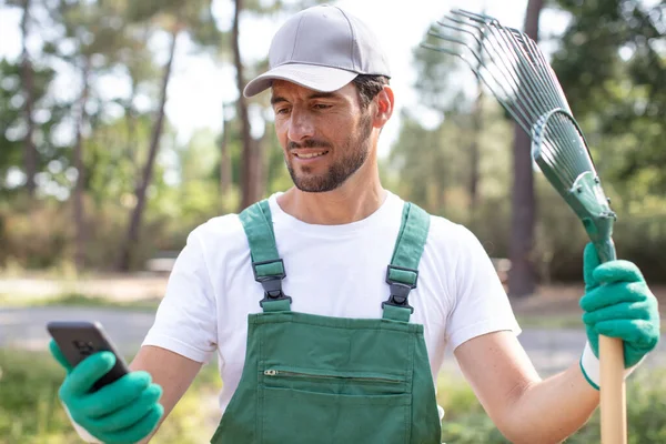 Jardinero Masculino Con Rastrillo Recibiendo Mensaje Telefónico — Foto de Stock