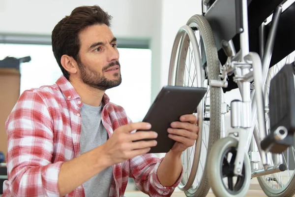 Junger Mann Repariert Rollstuhl Mit Tablet — Stockfoto