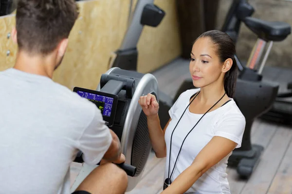 Personal Trainer Helping Male Client Using Rowing Machine — Stock Photo, Image