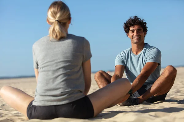 情侣们坐在室外海滩上做瑜伽练习 — 图库照片