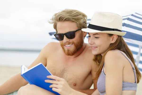 幸せなカップルはビーチで本を読むのが大好きです — ストック写真