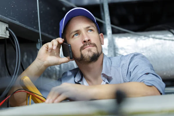 Technicus Met Behulp Van Zijn Telefoon Tijdens Het Repareren Van — Stockfoto
