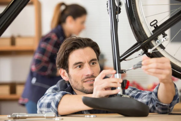 自転車のサドルの高さを調整するオスの整備士 — ストック写真