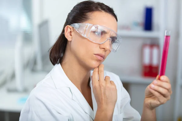 Cientista Fêmea Óculos Proteção Verificando Substância Líquida Vermelha — Fotografia de Stock