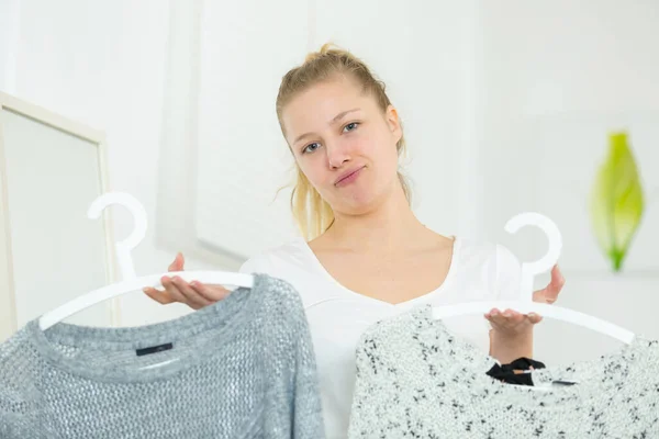 Chica Sosteniendo Dos Blusas Diferentes Perchas —  Fotos de Stock