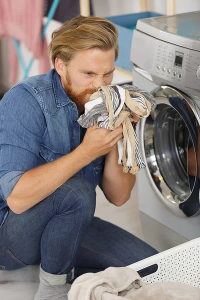 年轻人洗衣服的时候闻到衣服的味道 — 图库照片