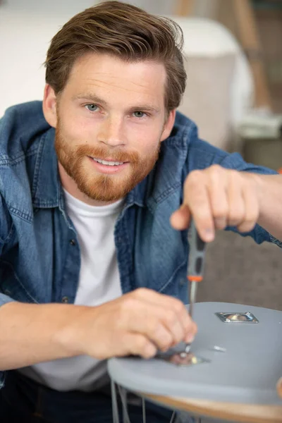 Glad Man Samlar Vitt Träbord Med Handskruvmejsel — Stockfoto