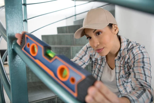 Bauarbeiterin Überprüft Treppengeländer Mit Wasserwaage — Stockfoto