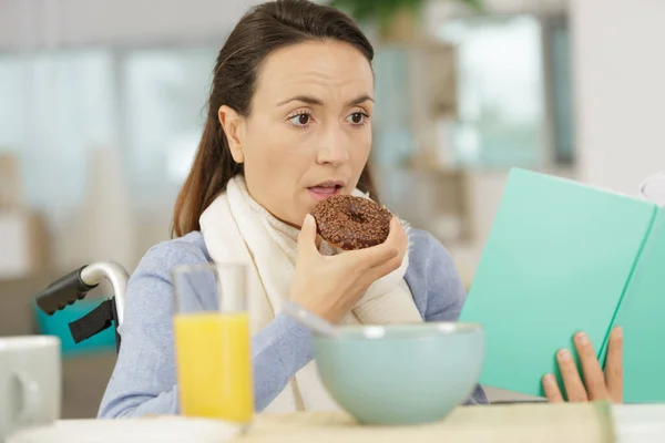 Jonge Gehandicapte Vrouw Eten Een Donut Tijdens Het Lezen Van — Stockfoto