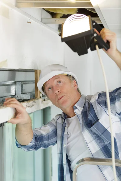 Dojrzały Pracownik Trzymający Lampę Przestrzeni Dachowej — Zdjęcie stockowe