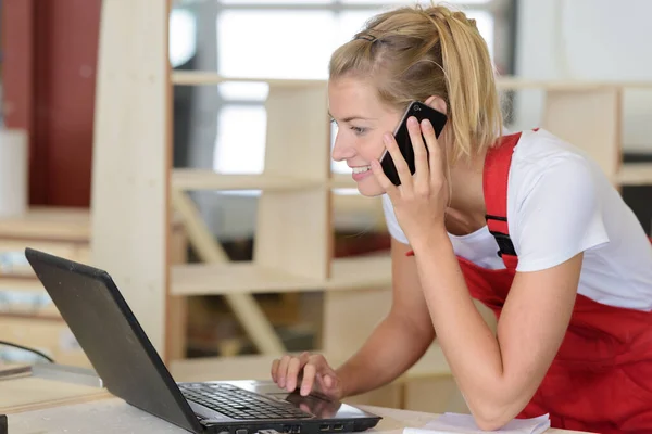 職場でノートパソコンを使って赤い服を着た女性労働者が — ストック写真