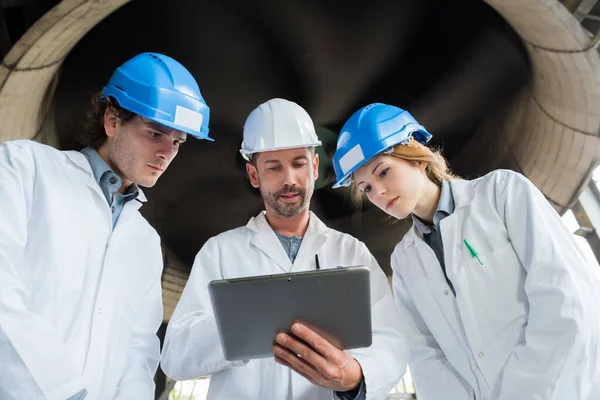 Tre Lavoratori Piedi Sotto Turbina Guardando Tablet — Foto Stock