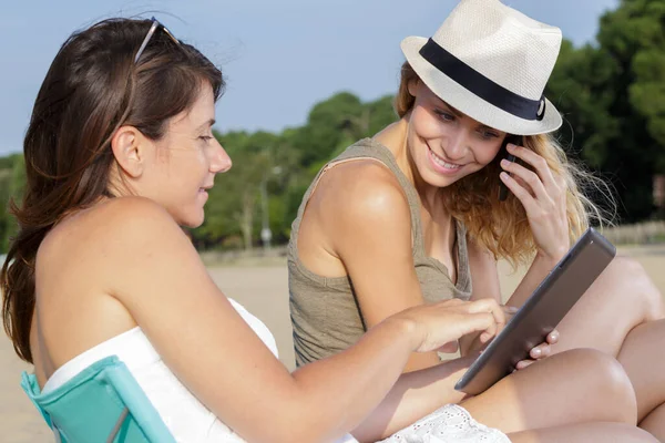 Två Unga Kvinnor Stranden Med Surfplatta Och Smartphone — Stockfoto