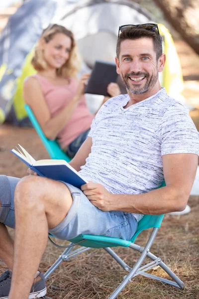 若く陽気な夫婦がテントの近くで読書をし — ストック写真