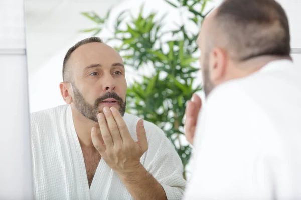 剃った後に化粧水で肌を治療する健康な男性 — ストック写真