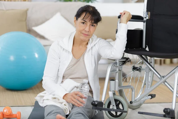 Senior Woman Sitting Floor Next Wheelchair — стоковое фото