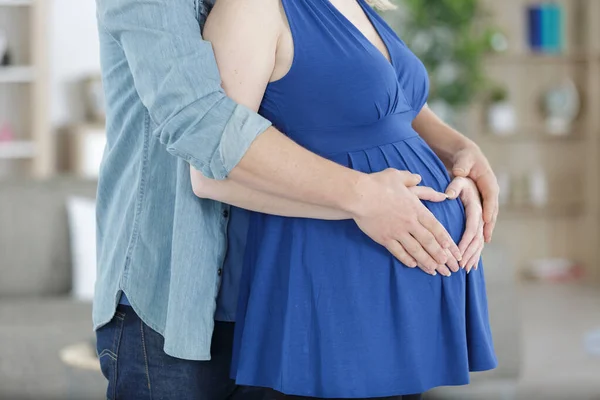 一对怀孕的夫妇在屋里拥抱 — 图库照片