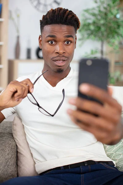 Förvånad Afrikansk Man Håller Telefonen Tittar Mobiltelefon — Stockfoto