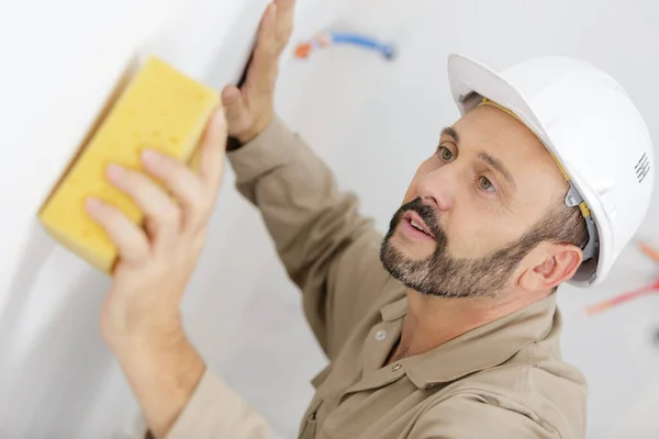 成熟的建筑工人在墙上用海绵 — 图库照片