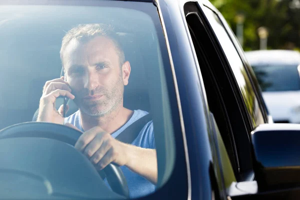 man driving a car with a phone