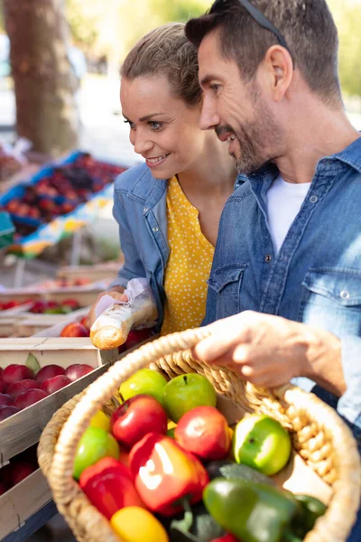 快乐的夫妻在市场上买水果和蔬菜 — 图库照片