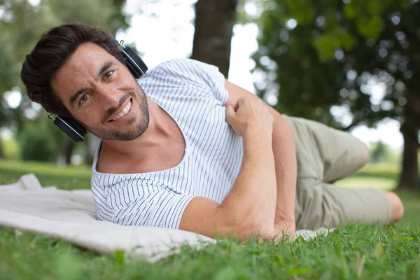 Genç Adam Çimlerin Üzerinde Tabletten Müzik Dinliyor — Stok fotoğraf
