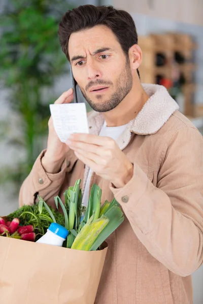 Uomo Con Generi Alimentari Guardando Sua Ricevuta Con Shock — Foto Stock