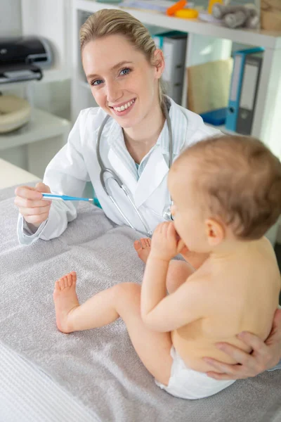 体温計を持った赤ちゃんを持つ女性の小児科医は — ストック写真