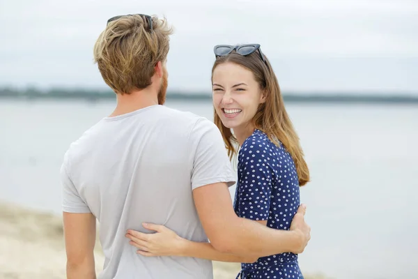 幸せなカップルが一緒にビーチで抱き合って笑っています — ストック写真